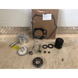 Club Car FE350 96-UP "Basic" Engine Rebuild Kit components, such as a gasket, piston, valves, and filter, organized on a metal-textured surface.