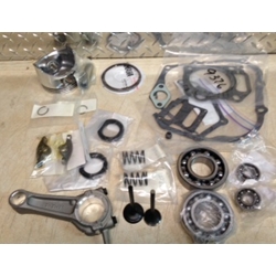 The Yamaha Engine Rebuild Kit G21-G29, featuring gaskets, bearings, and valves among other components, is laid out on a surface in a workshop.